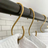 Brass hooks holding a white waffle weave shower curtain