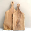 Two wooden chopping boards with handles on a marble top