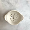 A white tea strainer with spiral perforated patterns