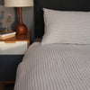 Sustainable Stripe Linen Pillow and Duvet on a Bed with a side table just in site