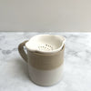 A white tea strainer in a beige and white mug