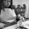 A Woman In An Apron Hand-pouring Rapeseed Wax Tealight Candles